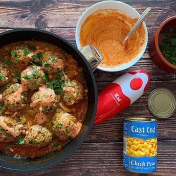 Top-down rustic scene with meatballs, sauces, chickpeas, herbs, and Kitchen Mama can opener on a wooden table.