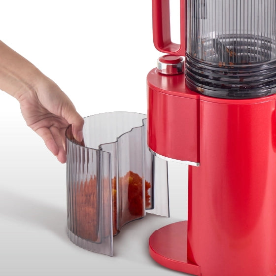 Removable pulp container being taken out from the Kitchen Mama EverVive cold press juicer for easy cleanup.