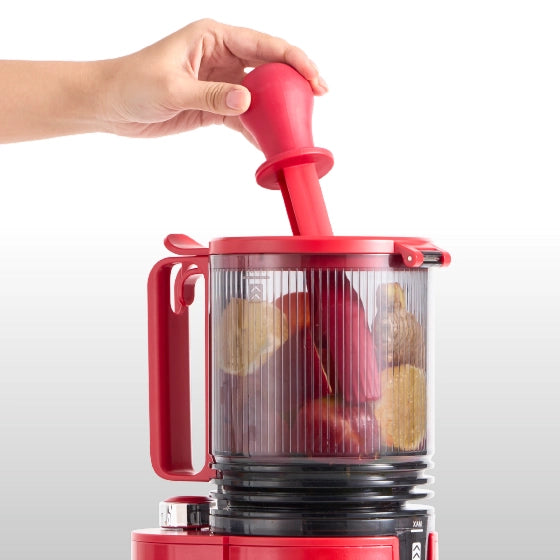 Large-capacity hopper of the Kitchen Mama EverVive cold press juicer being loaded with fresh produce using the food pusher.