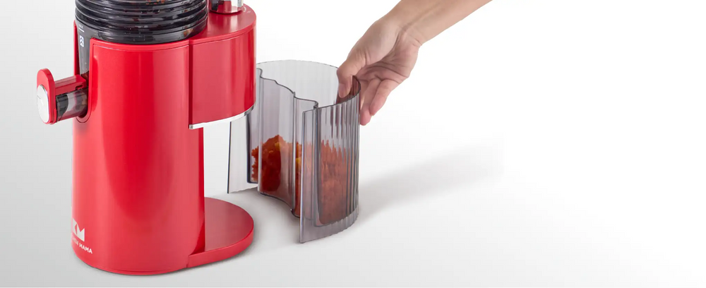 Removable pulp container being taken out from the Kitchen Mama EverVive cold press juicer for easy cleanup.