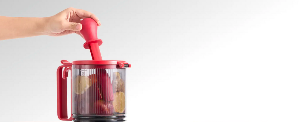 Large-capacity hopper of the Kitchen Mama EverVive cold press juicer being loaded with fresh produce using the food pusher.